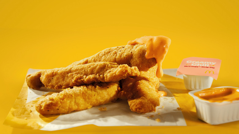 Sauce drips from a McDonald's McCrispy Strip that is piled on top of others
