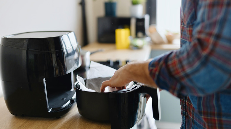 Cook prepping an air fryer with parchment paper