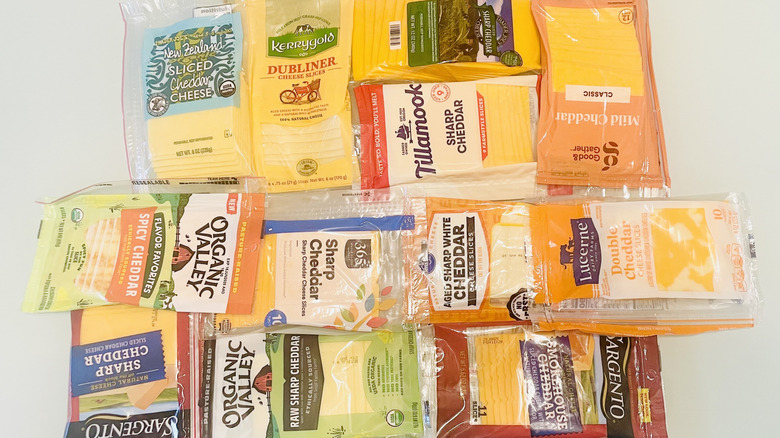 Collection of different types of sliced cheddar cheese in store packaging